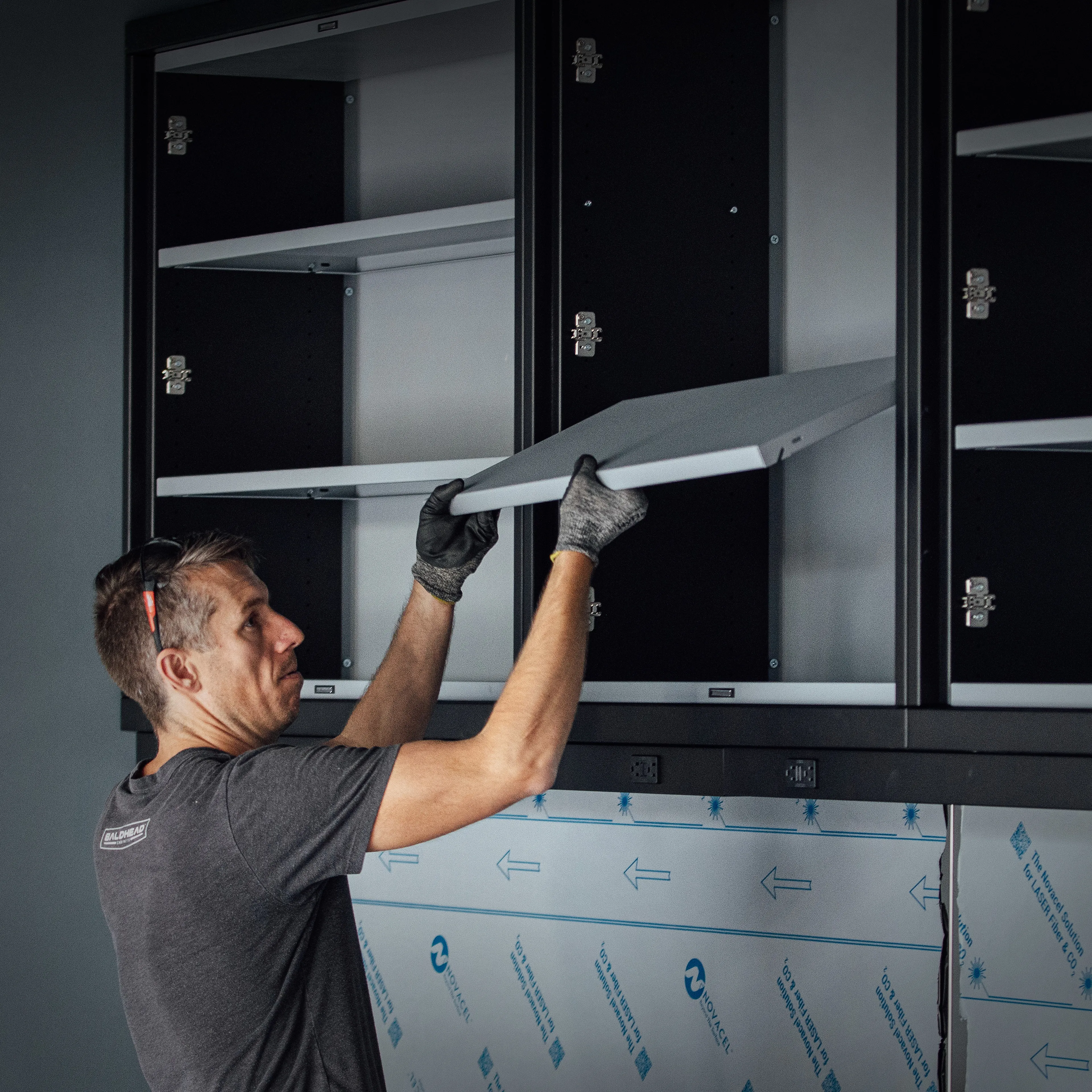 A worker handling components for high quality custom metal cabinets, showcasing the manufacture of high quality built cabinets for tools and gear.