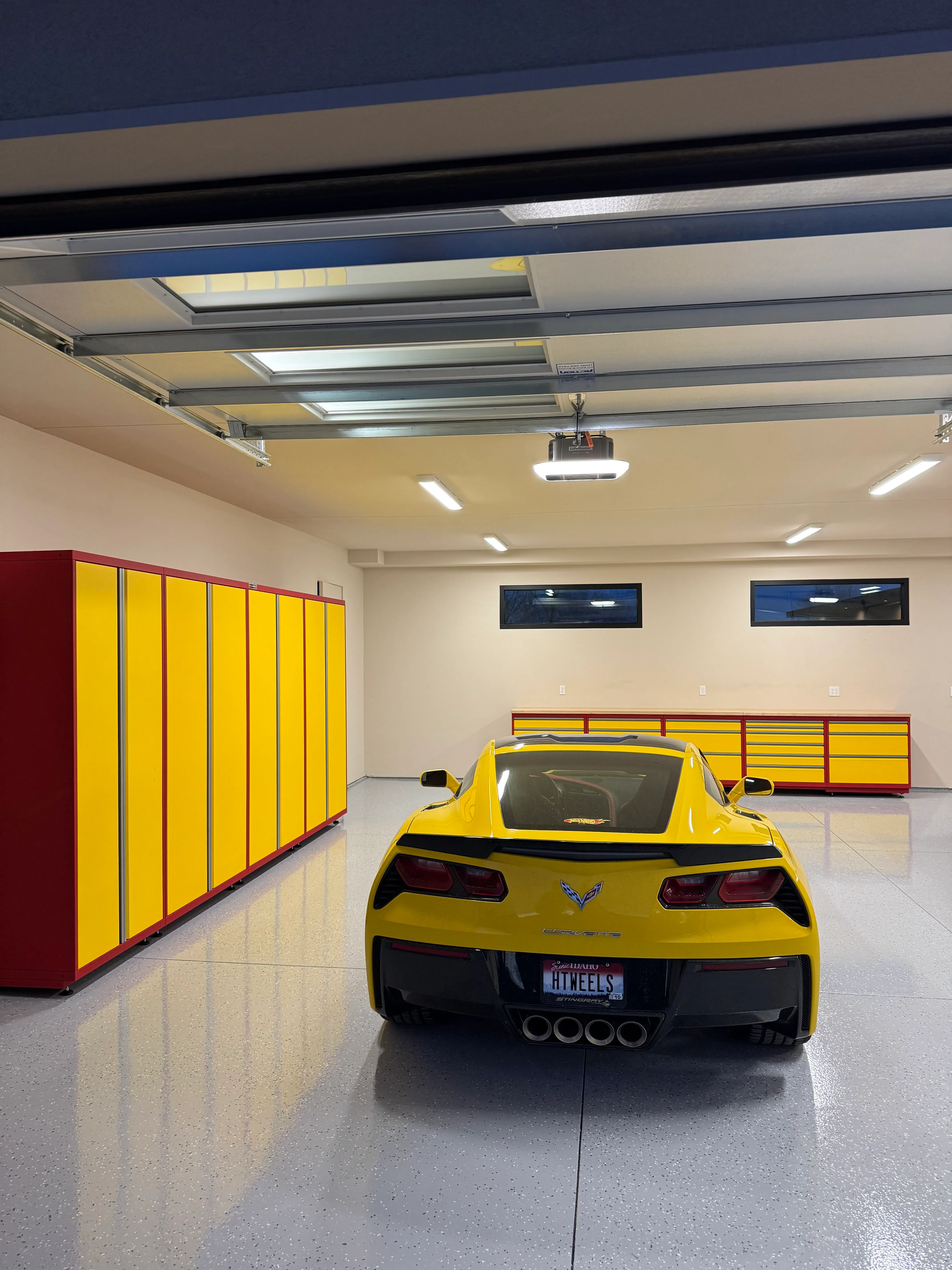 Modern garage setup featuring custom yellow and red Baldhead Cabinets with sleek, high-gloss finish, perfectly matching a yellow Corvette. Premium garage storage and design solution for automotive enthusiasts seeking bold style and maximum functionality.
