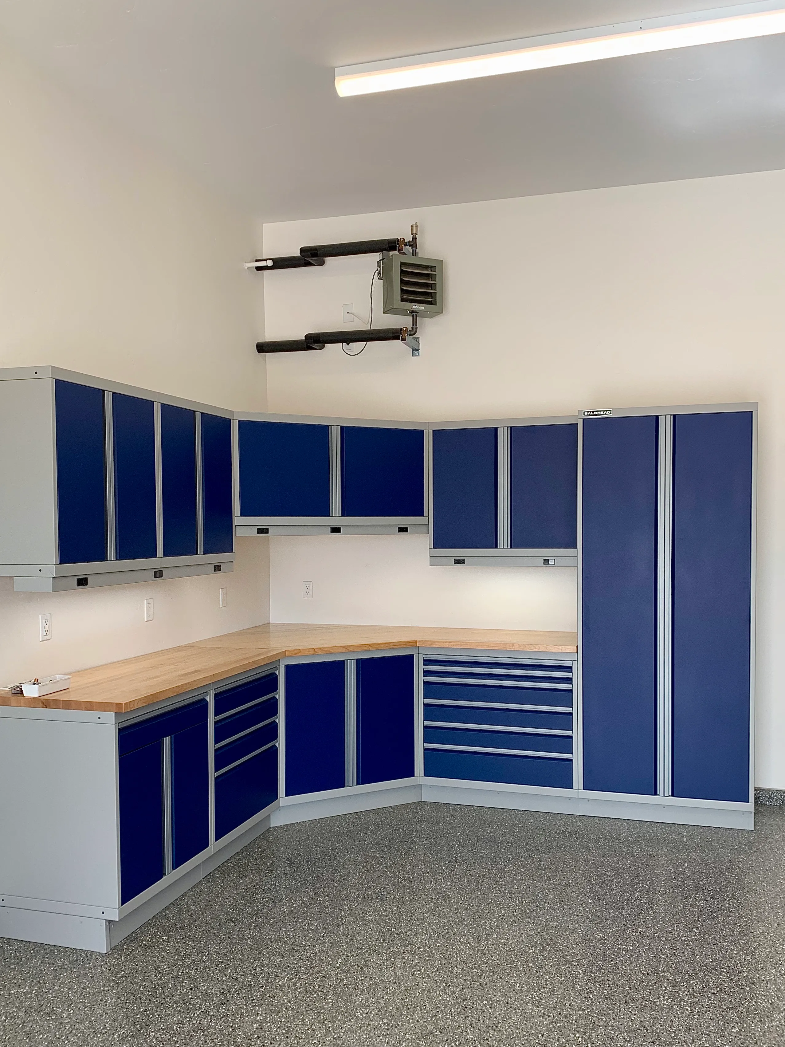 Bright blue and silver custom garage cabinets with butcher block countertops and corner drawer configuration by Baldhead Cabinets — premium metal cabinetry for organized and efficient home garage workspaces