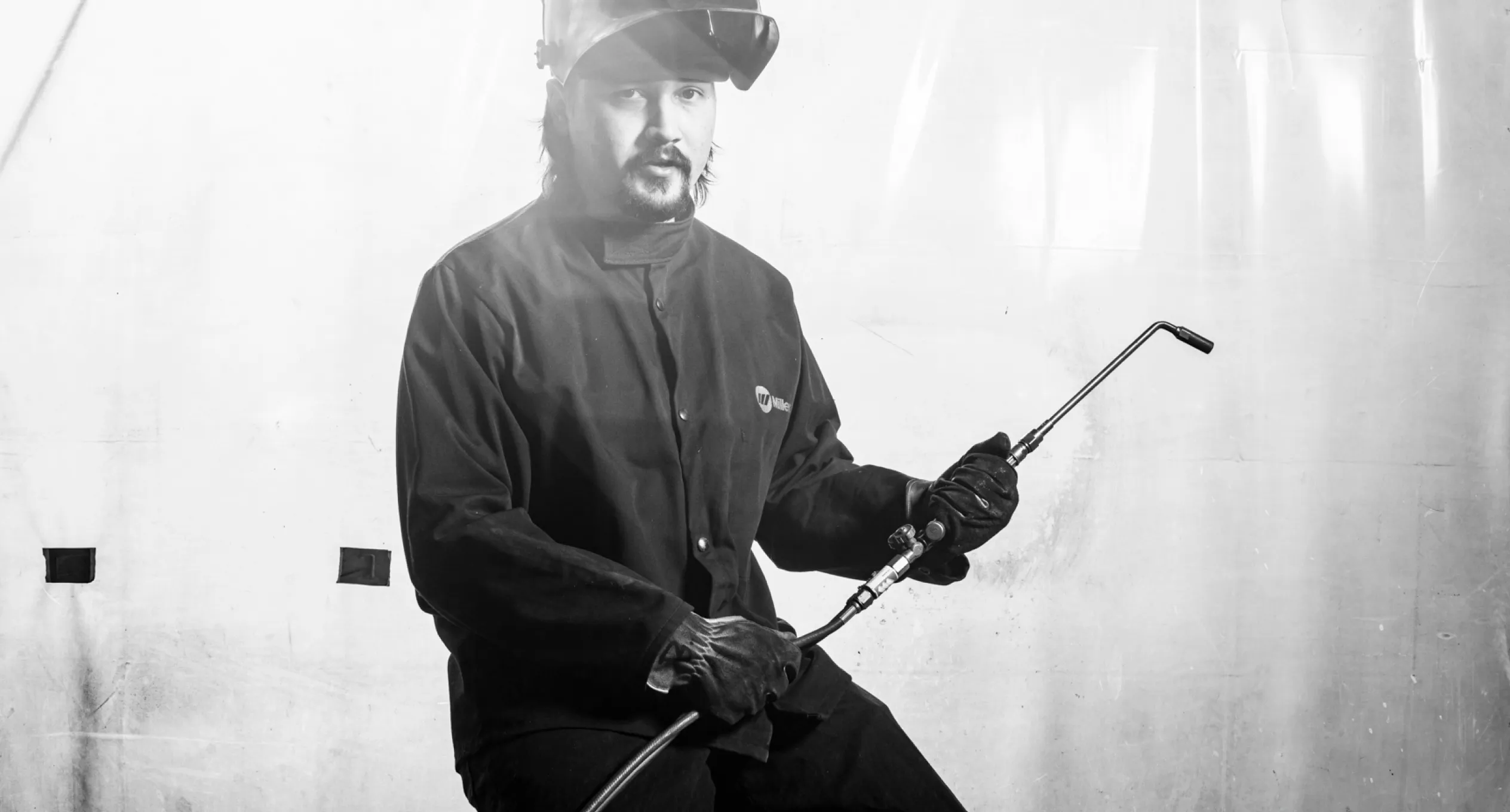 Skilled worker in protective welding gear holding a welding torch, showcasing craftsmanship at Baldhead Cabinets.