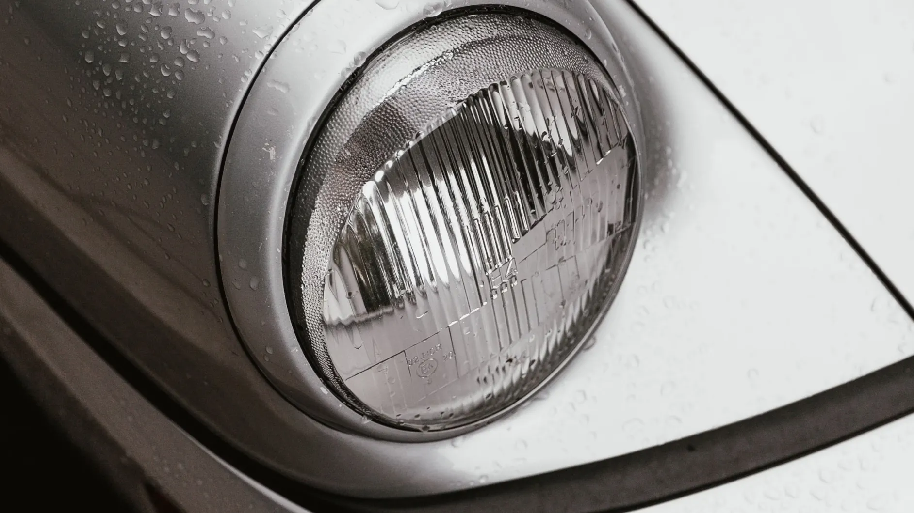 Close-up of a classic car headlight with water droplets at Baldhead Cabinets