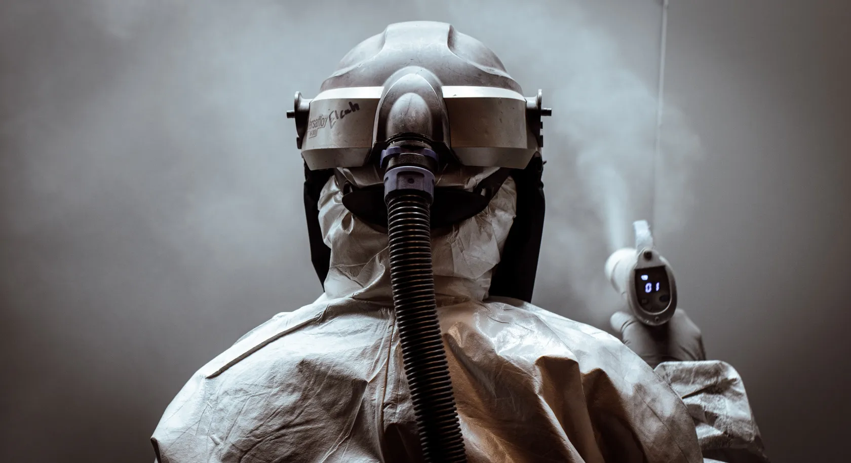 Worker in a protective suit and helmet using a heat gun, emphasizing the precision and care taken in the finishing process of custom cabinetry.