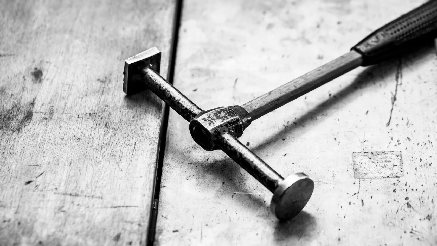 Close-up of a metalworking tool, specifically a jeweler's hammer, on a workbench.